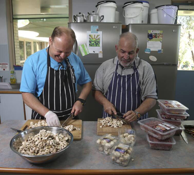FILLING A NEED: Birallee Park Neighbourhood House volunteers Brett Ashlin and Rob McGrandles prepare food for the Our Table To Yours program, which has supplied more than 60,000 meals in eight years. Picture: ELENOR TEDENBORG