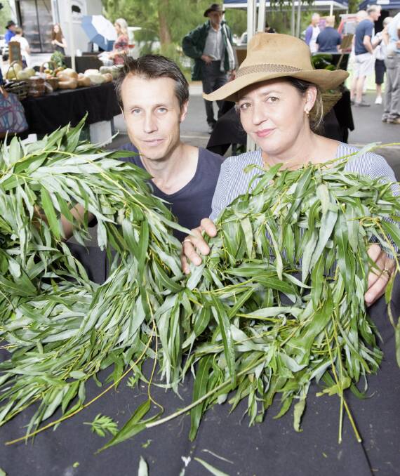 THIS IS WHAT WE DO: Aaron Gray-Block and Nadine Rofe hold willow wreaths in memory of their late father as the market goes on around them. Picture: SIMON BAYLISS