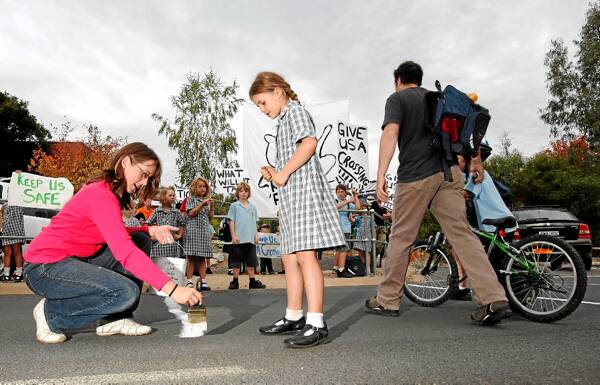Fiona Reddaway and Lara Pasquenelli, 7, paint a school crossing on the road. Picture: JOHN RUSSELL
