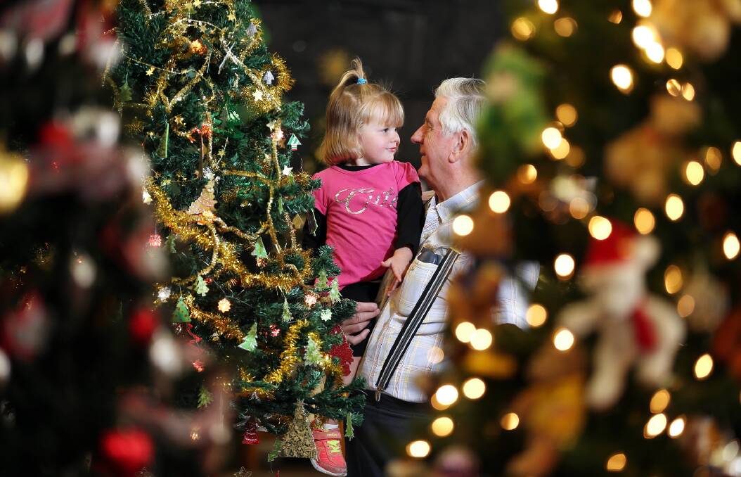 It’s a meeting of the minds over Christmas trees for Lexie Rollings and her great grandfather, Bruce James, at the tree festival. Picture: John Russell