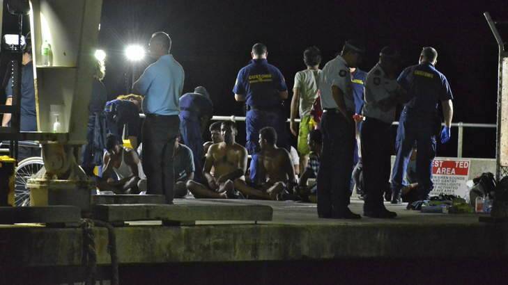 Customs officials and rescue personnel watch over survivors of the capsized boat at Christmas Island docks on Tuesday night. Photo: Sharon Tisdale