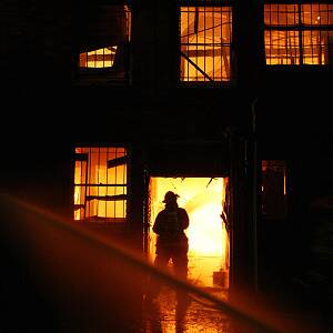 CFA officers fight the flames at the rear of one of the Dean Street stores destroyed this morning.