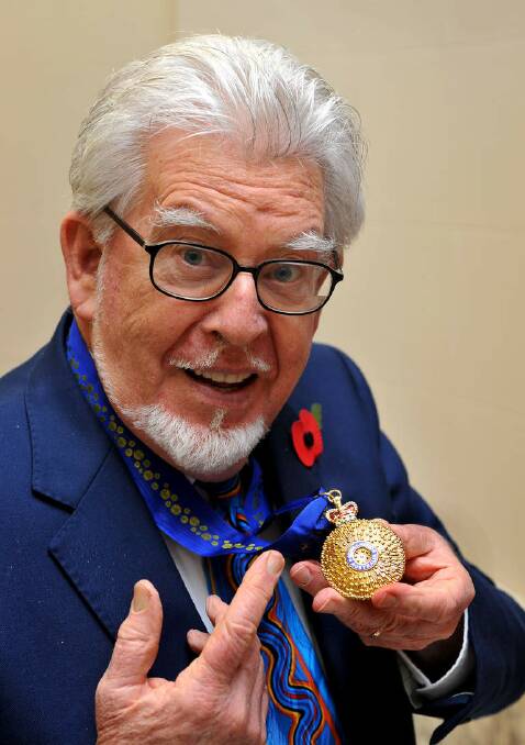 Australian broadcaster and artist Rolf Harris holds the Officer of the Order of Australia, presented by the High Commissioner John Dauth, at Australia House in London, England in 2012. Photo: WPA