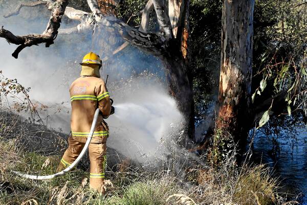 Firefighters put out a small fire beside the bike path on Gateway Island. Picture: JOHN RUSSELL