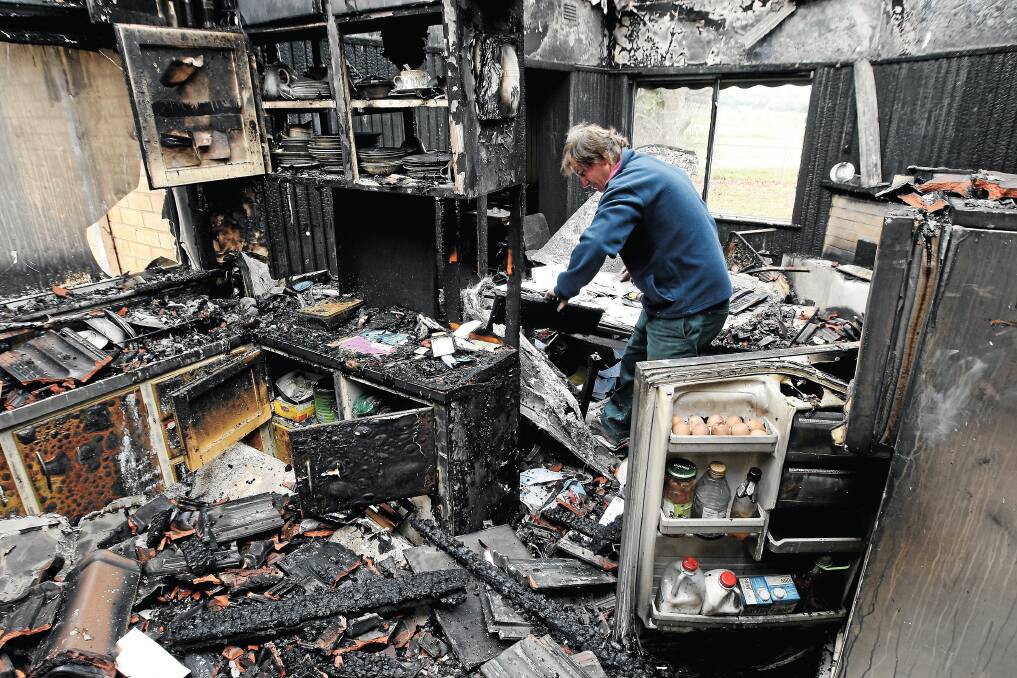 Brent Nicoll picks through the ruins of his father’s Whorouly home after it was gutted by fire. Picture: JOHN RUSSELL