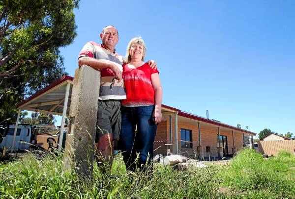 Tony Halpin and his wife, Helen, outside their almost completed home 12 months after the fire. Mr Halpin said he would again fight to save his family home. INSET: Tony Halpin sits in his utility, his house burning behind him. Pictures: JOHN RUSSELL