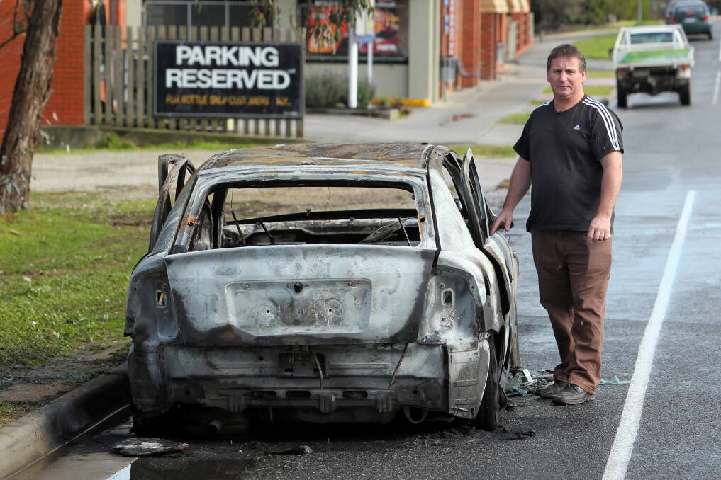 Blazing Stump manager Pat Williams with the scorched shell of the car set on fire outside the hotel early yesterday.