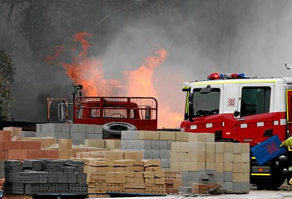Flames leap above the CFA trucks. It is believed the blaze started in a wood pile.
