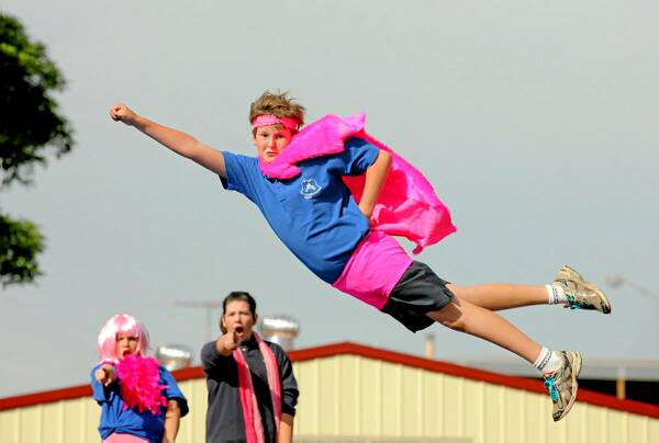 St Augustine’s Primary School students Ella Rafferty, 12, and Jordyn Causer, 11, watch on as Charlie King, 12, plays Superman during the school’s pink fund-raiser yesterday. Picture: DAVID THORPE
