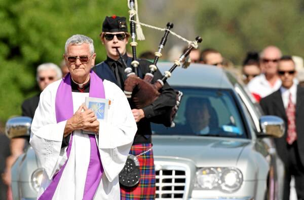 Monsignor John White leads mourners into Greta cemetery for Ned Kelly’s burial yesterday.
