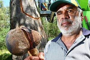 Dick Murray, of Wodonga, one of the traditional owners of the area, holds a genuine stone axe used for cutting a section of bark from a gum tree, as part of the process of making a traditional Aboriginal canoe.
