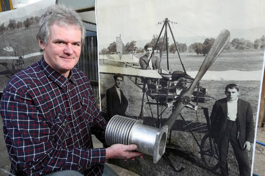 Michael Browne with a cylinder barrel in front of a photograph of the aviators preparing for their 1913 flight.