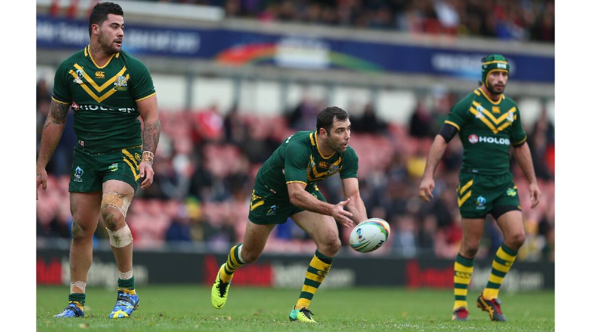 Cameron Smith (C) of Australia plays the ball as Andrew Fifita (L) and Jonathan Thurston (R) look on during the Rugby League World Cup Quarter Final match between Australia and the USA. Photo: Getty Images.