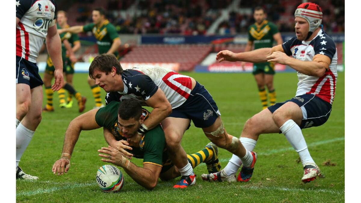Greg Inglis of Australia dives over the line ahead of Kristian Freed of USA to score his try during the Rugby League World Cup Quarter Final match between Australia and the USA. Photo: Getty Images.