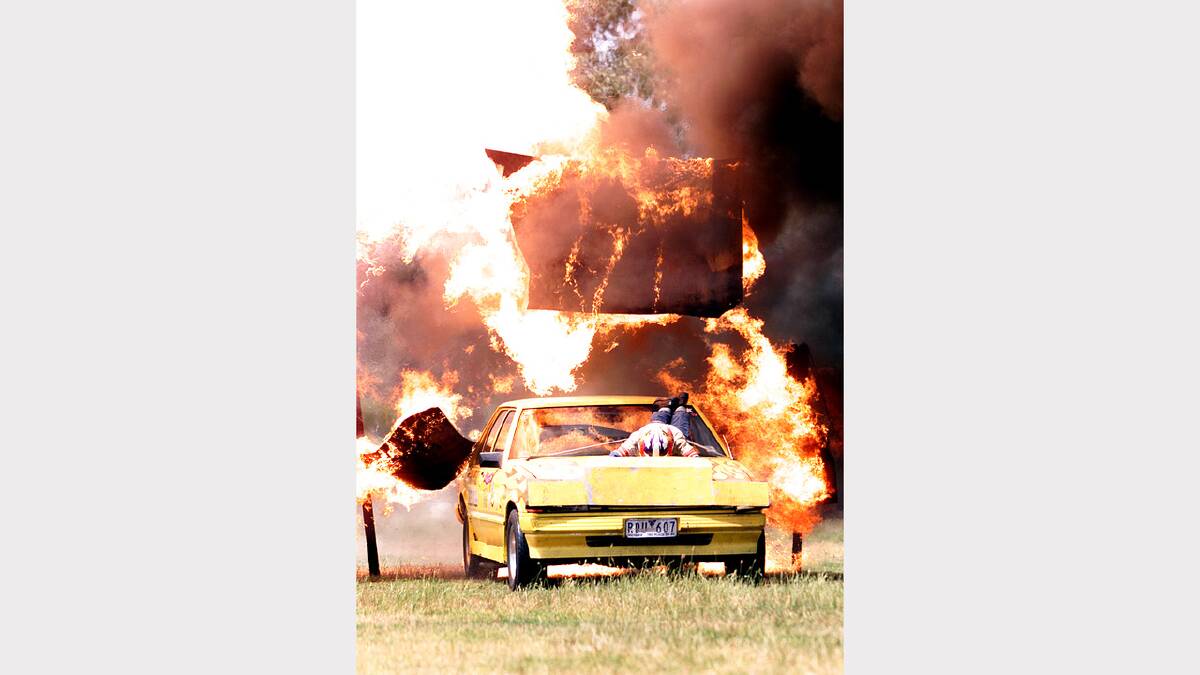 Ms Alex Lau,19, of Townsville is strapped to the bonnet of this car while Bill Luther drives through a wall of fire. This stunt, called the Triple Fire Wall, will be performed at the Albury Showgrounds. Picture: MATTHEW SMITHWICK