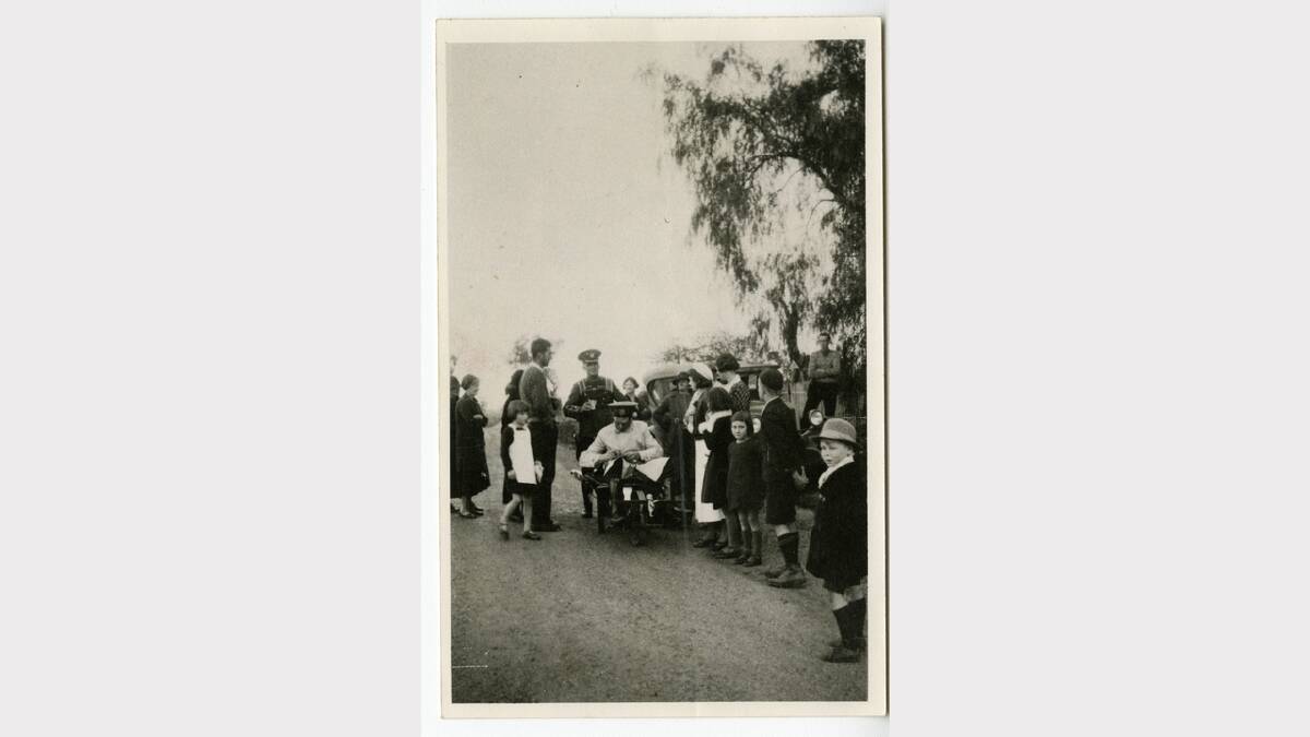 August 1935 photograph of a group of people, a car, a wheelbarrow near a tree on the roadside at Table Top. Cr. Darwin, the wheelbarrow pusher and Mr. W. Amiguet, the sitter, were on their way to Sydney from Melbourne as part of a bet. Picture: ALBURYCITY COLLECTION