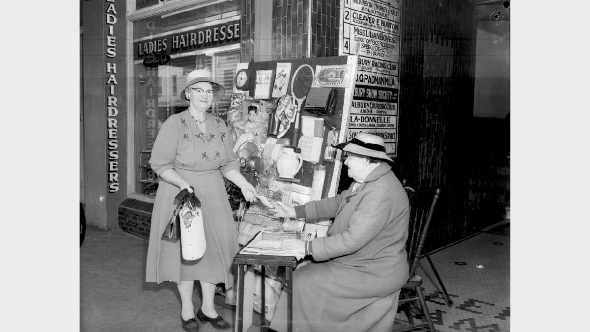 Sally Shipard, left, buys a Christmas stocking ticket from Mrs Miller at a stall outside Beehive Chambers in November 1960.