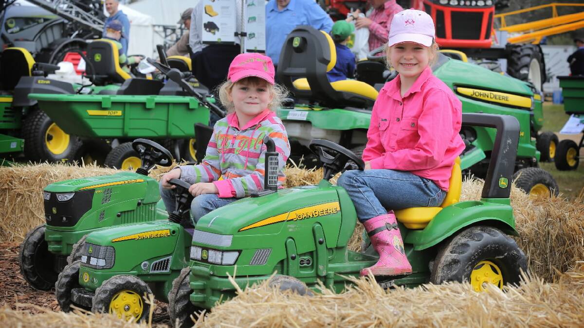 Chanel Thompson, 5, and her sister Lashae, 6, try out the mini John Deere tractors. Picture: TARA GOONAN