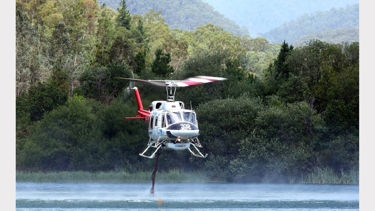A water-bombing helicopter refills with water from a dam in Harrietville during efforts to fight a bushfire burning between Harrietville and Mt Hotham.
