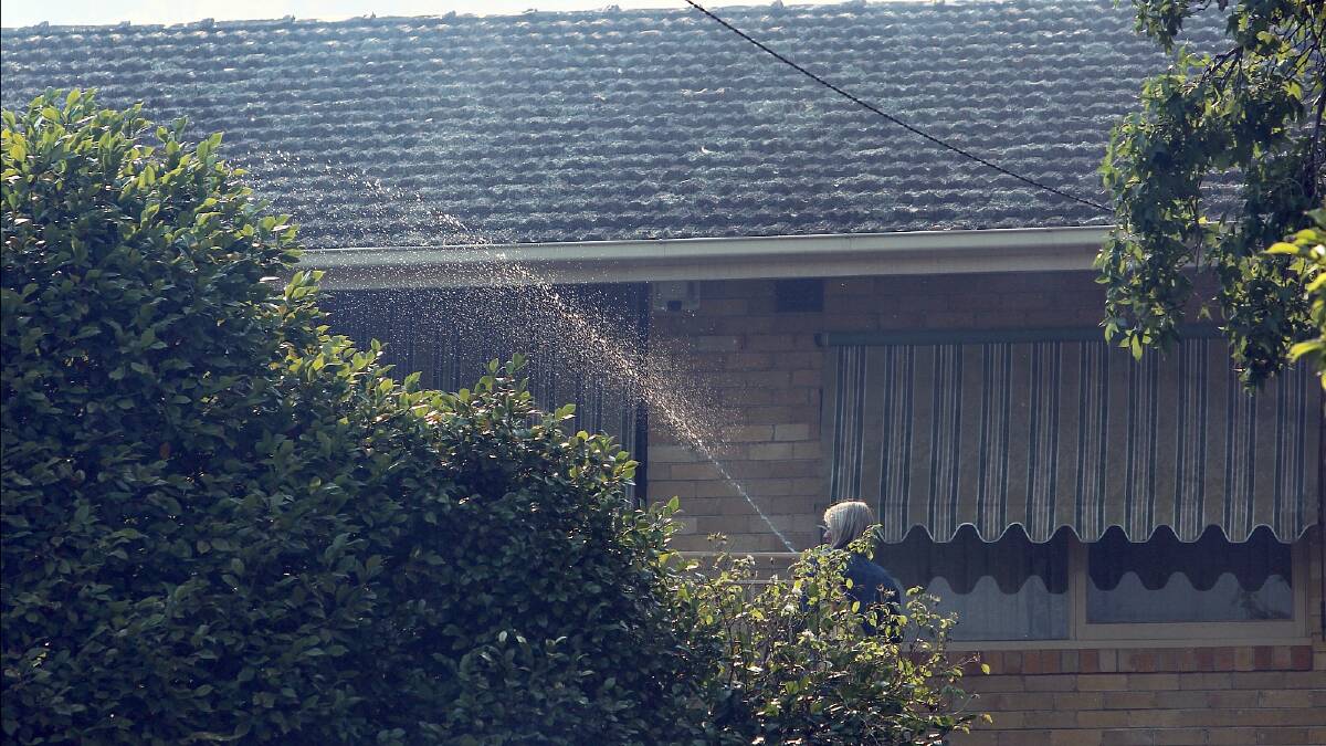 A Yambla Avenue resident uses a garden hose to wet down her property. PICTURE: Matthew Smithwick