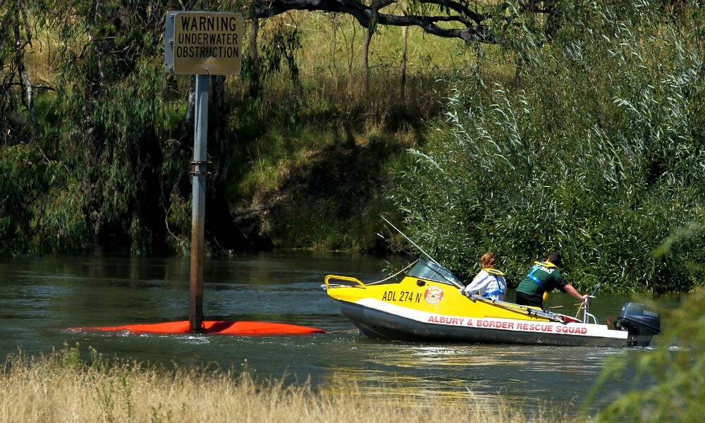 Members of the Albury and Border Rescue Squad retrieve a canoe which had been caught on a warning sign in the middle of the Murray River just upstream from the Spirit of Progress Bridge between Albury and Wodonga. The couple in the canoe were stranded clinging to the vessel until they were rescued. PICTURE: Matthew Smithwick.