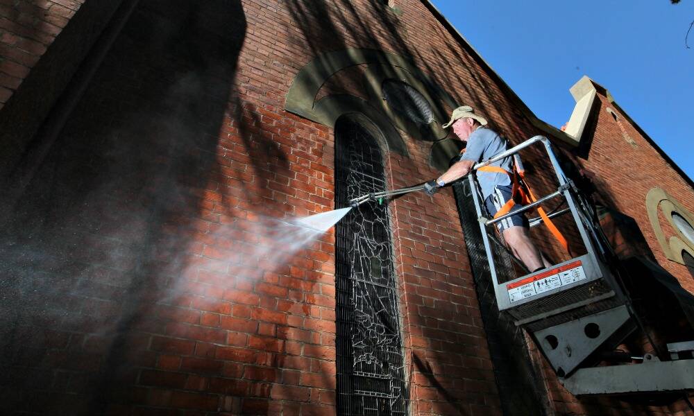 Rod Halsted cleans off the grime from the Wilson Street side of St David’s Uniting Church. It took two days to clean the church. Picture: DAVID THORPE