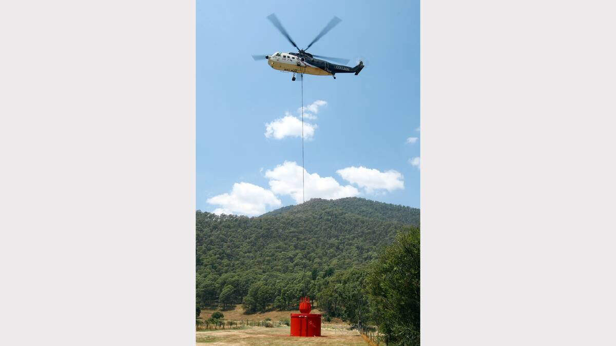 A water-bombing helicopter refills with water from a dam in Harrietville during efforts to fight a bushfire burning between Harrietville and Mt Hotham.