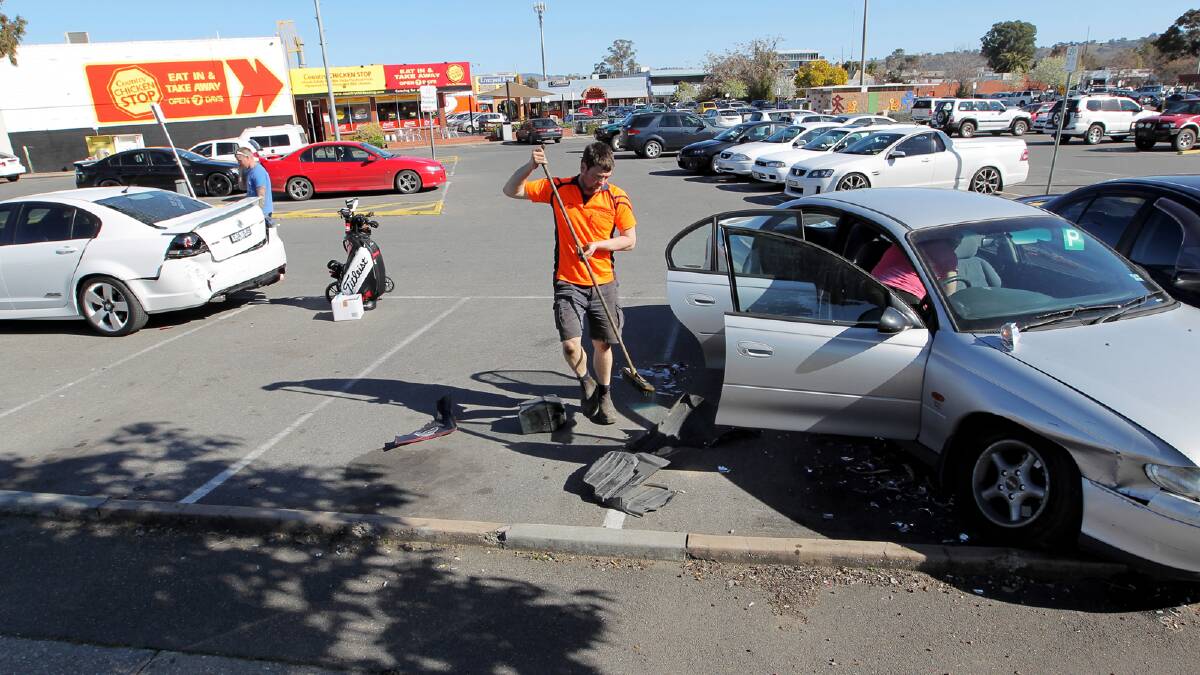 A tow truck driver cleans up glass and bits of car after the crash. Picture: DAVID THORPE