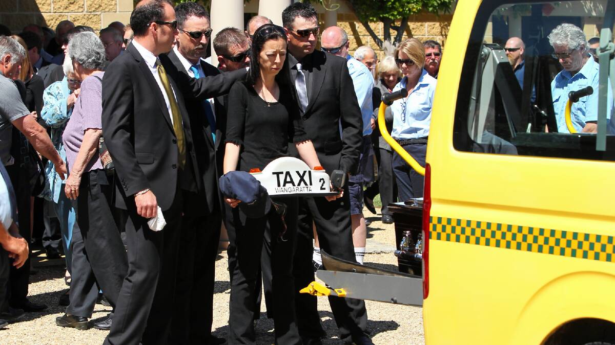 Michelle Love honours her father and his work, following Barry Love’s maxi-taxi hearse with a Wangaratta Taxi sign and his cap as it leaves for the Wangaratta Cemetery. Picture: MATTHEW SMITHWICK