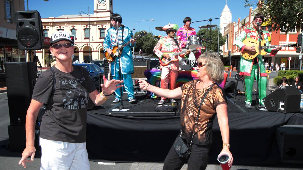 The Melbeats dressed up in colourful Beatles costumes to entertain the crowd, including Judy Nurmi, of Albury, and Kerrie Grady, of Wodonga, who enjoyed a dance in Dean Street. Pictures: PETER MERKESTEYN