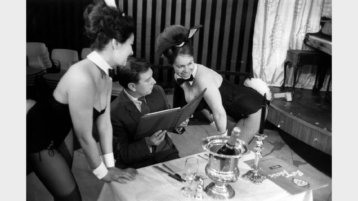 11th February 1963:  Two Bunny Girls serving a customer with a champange lunch at London's Playboy Club.  