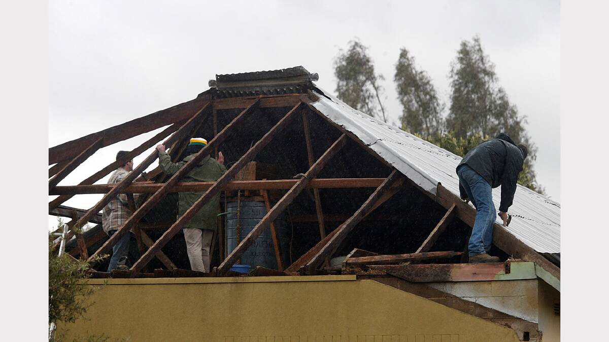 A Myrtleford family try to patch the roof torn from their home. June, 2010.