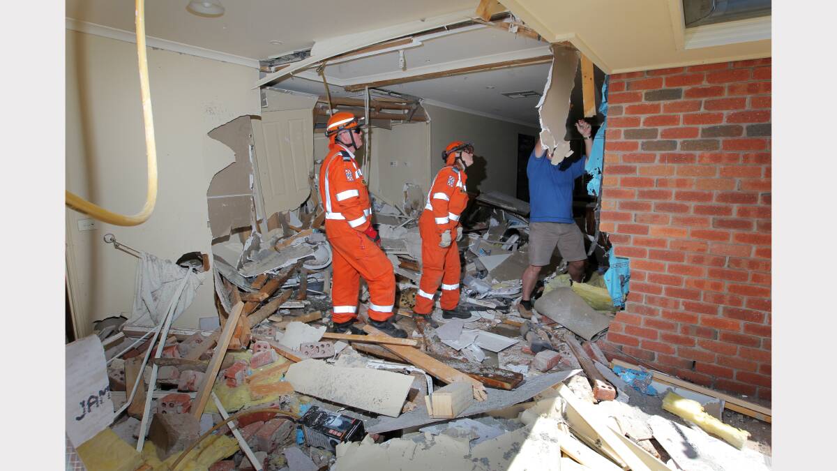 SES crews inspect the damage after the car crashed through the bathroom wall. 