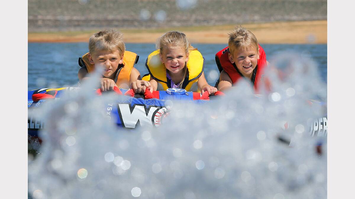 Siblings Noah, 9, Ruby, 3, and Jacob Collings, 6, of Pakenham, cool off on the biscuit at Lake Hume.