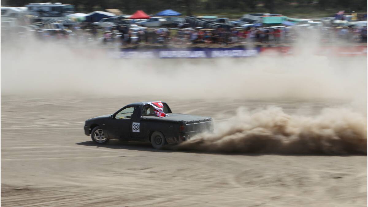 A black ute kicks up the dust in the finals of the circlework competition. 