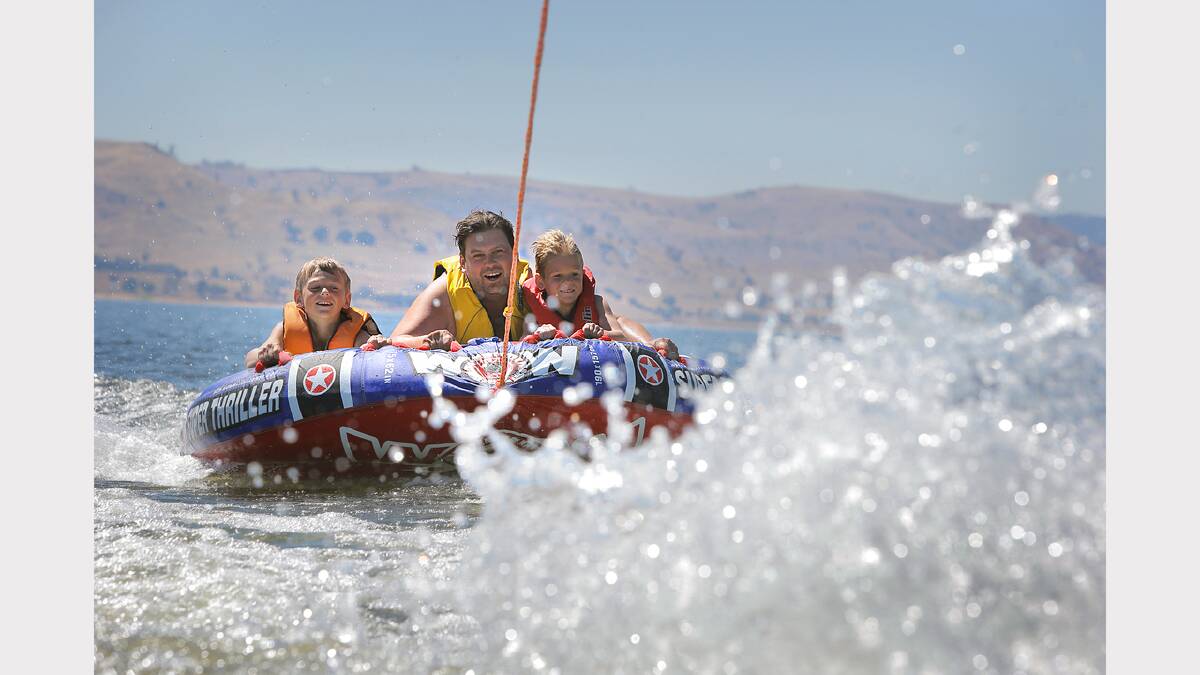 Siblings Noah, 9, Ruby, 3, and Jacob Collings, 6, of Pakenham, cool off on the biscuit at Lake Hume.