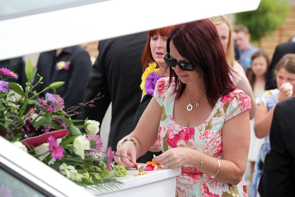 The girls' mother, Debbie Andrew, places flower petals on the casket. 