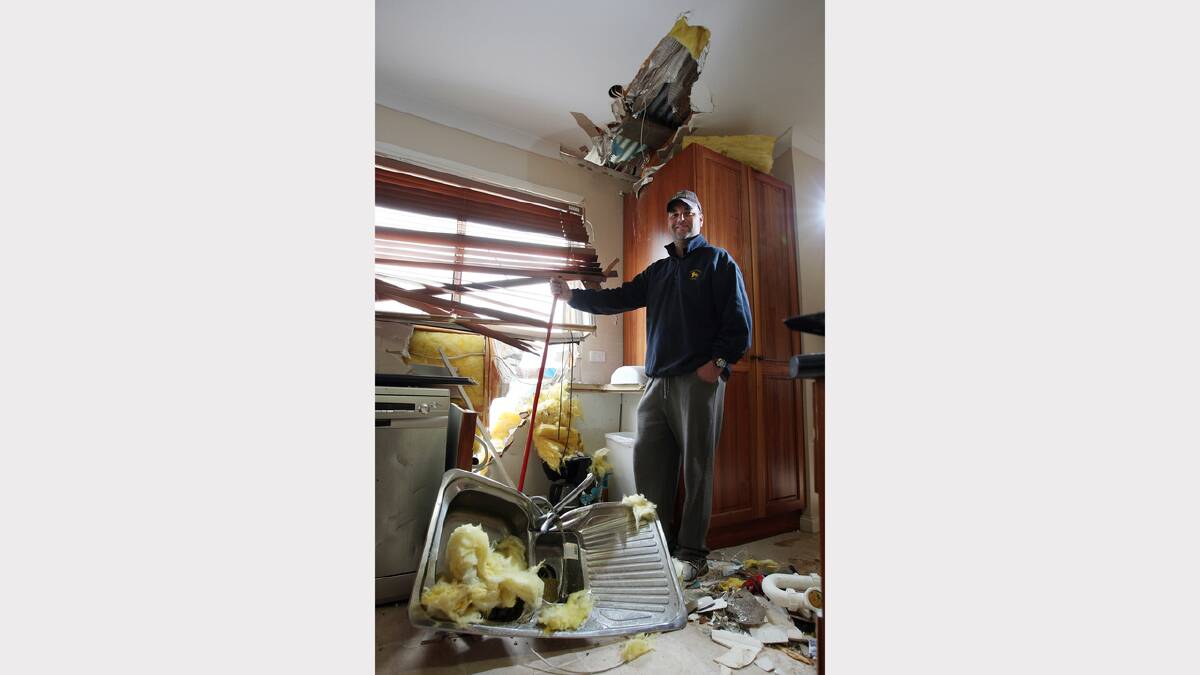 This man cleans up the mess after his shed roof smashed through into his kitchen in Myrtleford. June, 2010