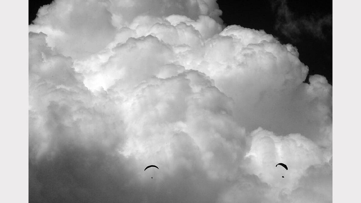 Paragliders glide in front of storm clouds during the championships in Bright. February, 2007.