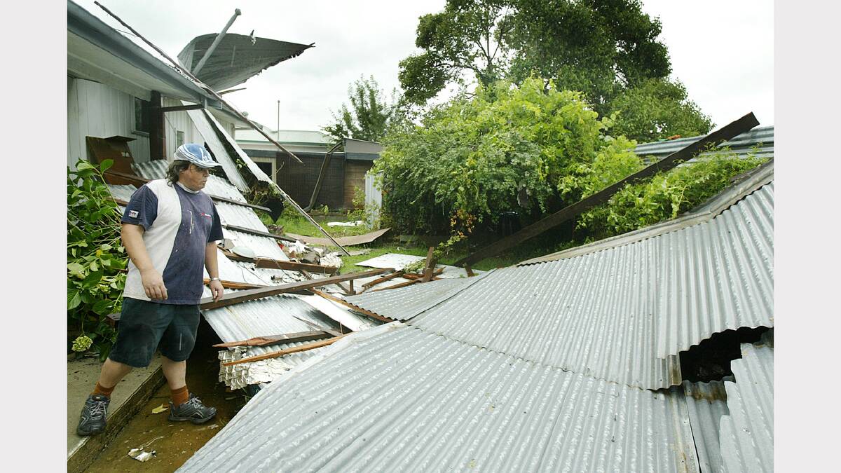 This man cleans damage after a roof he helped his mate build just months earlier came tumbling down in a storm. His mate had gone out to purchase insurance for the roof that morning. December, 2005.