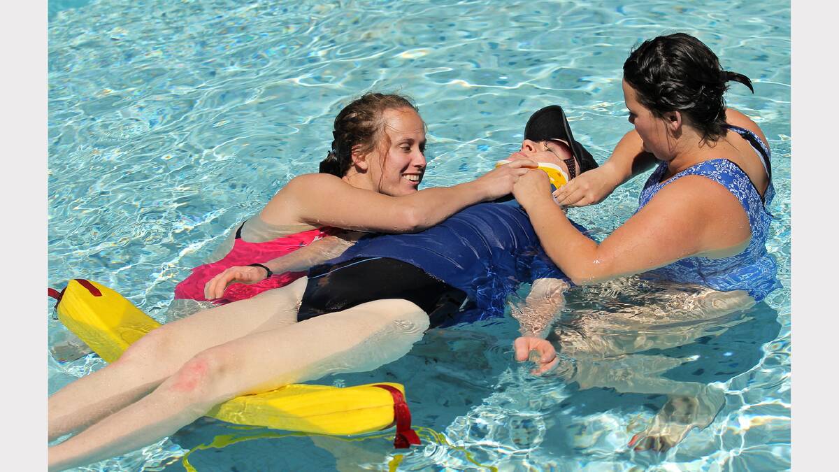Dani Brooks, Rebecca Mamouney and Jess Mitch take turns preparing each other to be moved on a spinal board.