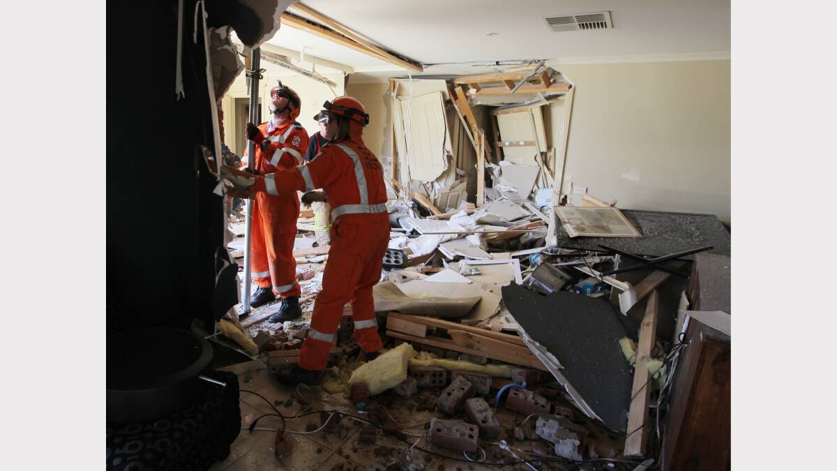 SES crews inspect the damage after the car crashed through the bathroom wall. 