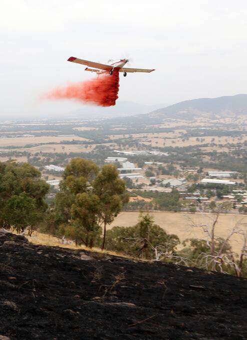 Fire retardant is dropped on the smouldering hill. 