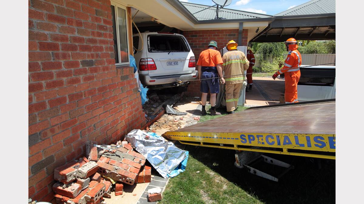 Fire, SES and RACV crews work to remove the car from the house.