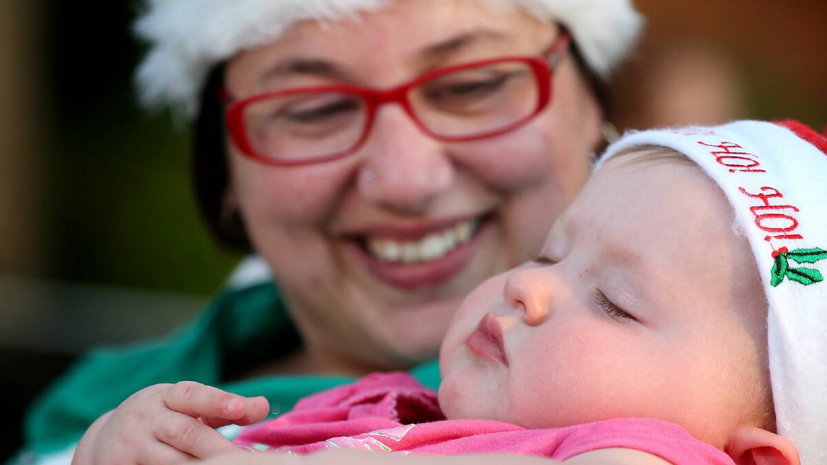 Stacey Packer holds her 10-month-old daughter Zara Packer-McInnes as she falls asleep during her first carols. PICTURE: John Russell.