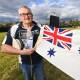 CHALLENGE AWAITS: Holbrook Submarine Museum curator Morrie Jeppensen holds a 1984 Australian white ensign in front of HMAS Otway to promote the Submariners Challenge. Picture: MARK JESSER