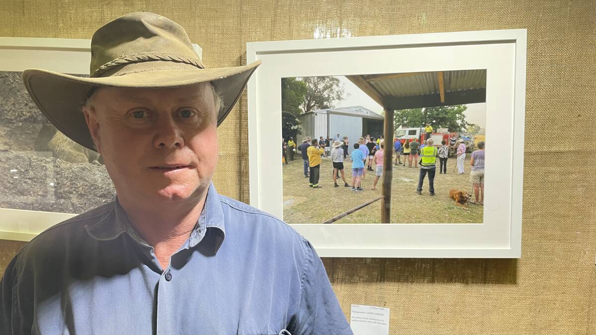 HEALING: Lankeys Creek resident and fire group captain John Hawkins in front of a photograph of himself addressing the Lankeys Creek community before the 2020 bushfires went through the district. Picture: VICTORIA ELLIS