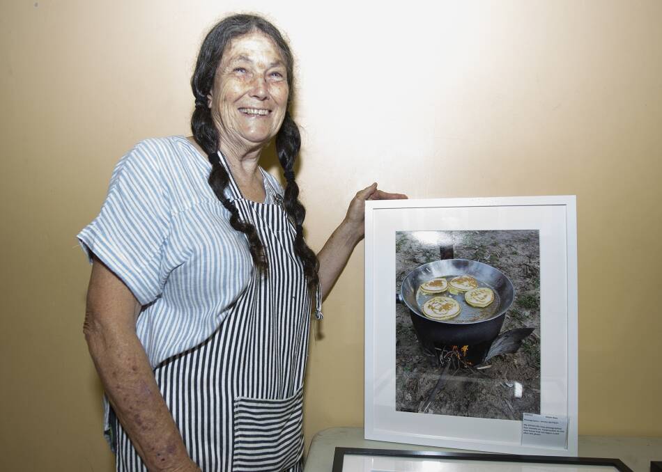 RECOVERY BREKKY: Bushfire recovery photography exhibtion curator Lorraine Hurlston with an image of a woman's camp oven cooked breakfast, while she waits for her new kitchen and house to be built. Picture: MICHAEL EGAN
