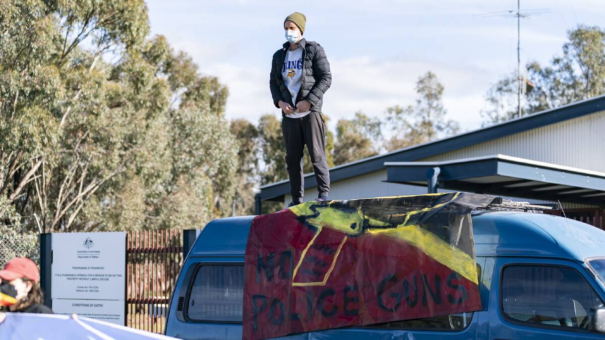 PROTEST: A Wage Peace group member stands on top of the bus, which blocks the entrance to the NIOA weapons manufacturing company in Benalla. Pictures: MATT HRKAC