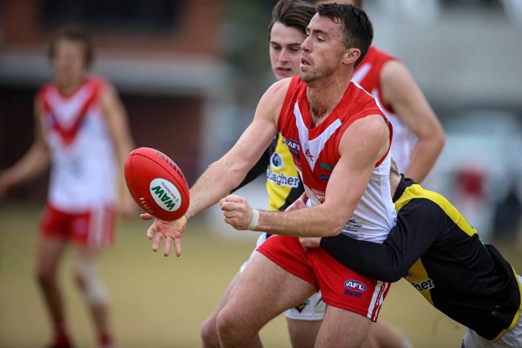 Henty's Dylan Hore disposes of the football just in time. Picture: JAMES WILTSHIRE
